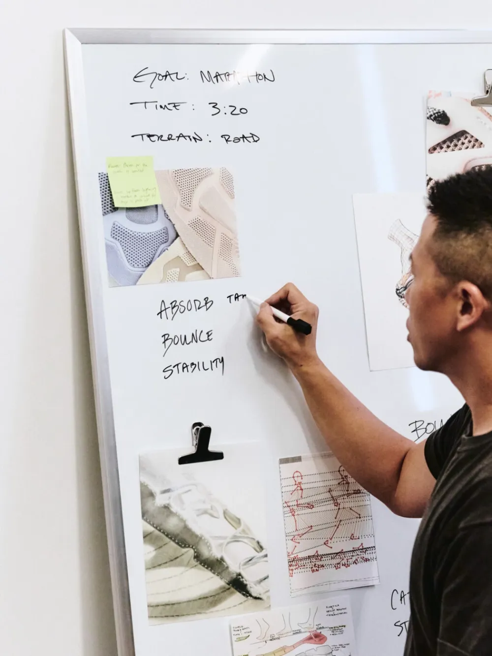 A RunReady co-founder writing Absorb, Bounce and Stability on a whiteboard of footwear and movement notes